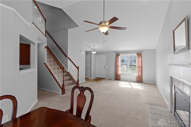 unfurnished dining area featuring light colored carpet, high vaulted ceiling, ceiling fan, and a tiled fireplace