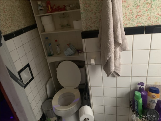 bathroom featuring toilet and tile walls