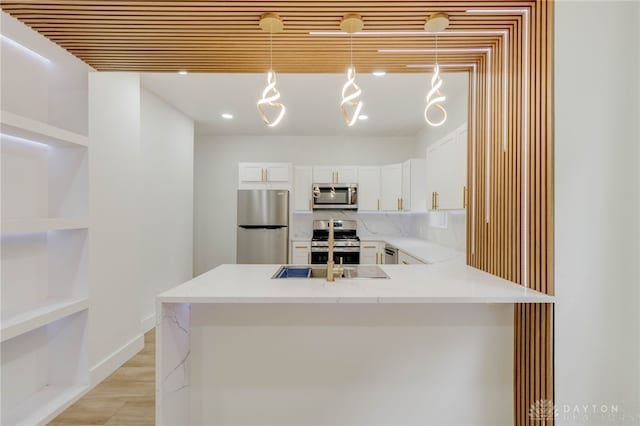 kitchen featuring decorative light fixtures, kitchen peninsula, sink, white cabinetry, and appliances with stainless steel finishes