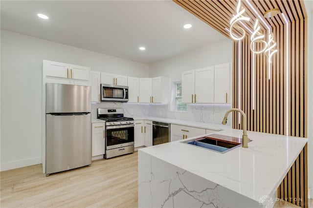 kitchen featuring white cabinets, stainless steel appliances, decorative backsplash, sink, and light stone counters