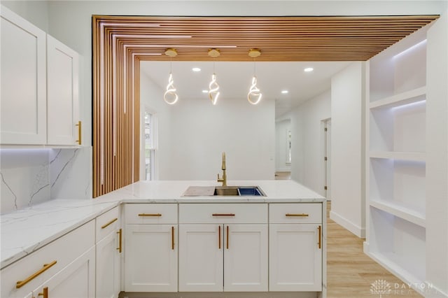 kitchen featuring decorative light fixtures, sink, and white cabinets