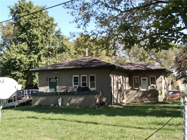 rear view of property featuring a lawn and stucco siding