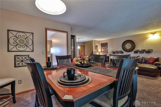 carpeted dining space featuring a textured ceiling