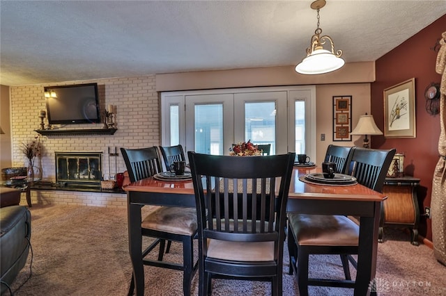 carpeted dining room with french doors, a brick fireplace, and a textured ceiling