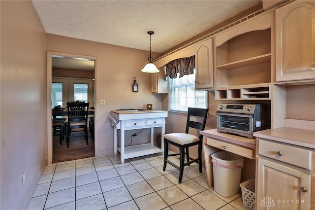 kitchen with light brown cabinetry, hanging light fixtures, and a textured ceiling