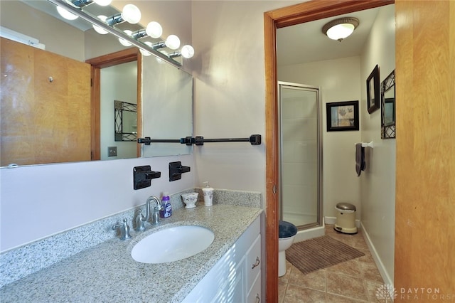 bathroom featuring tile patterned flooring, toilet, vanity, and a shower with shower door