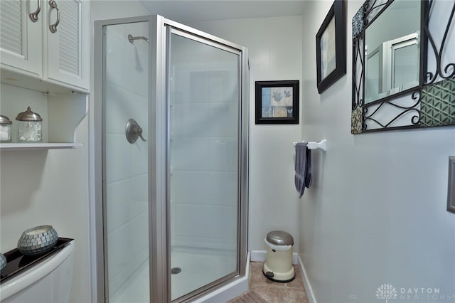 bathroom with toilet, an enclosed shower, and tile patterned flooring