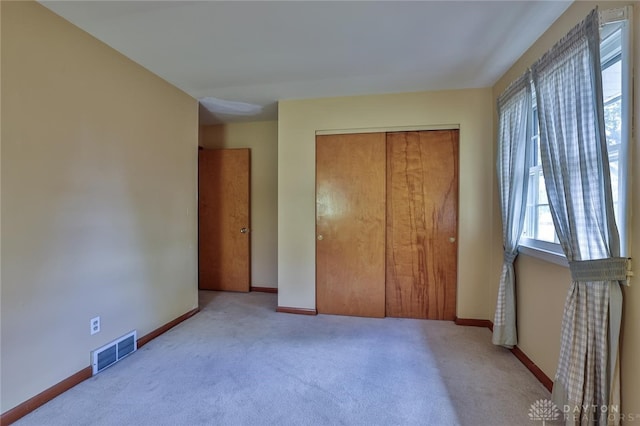 unfurnished bedroom with light colored carpet and a closet