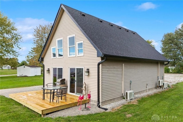 rear view of property featuring roof with shingles, a yard, central AC, and a wooden deck