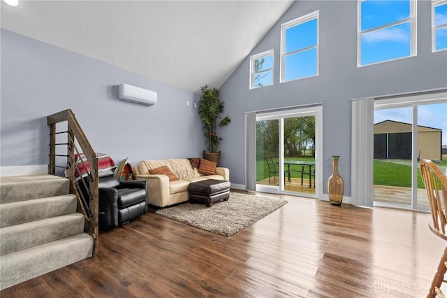 living area featuring high vaulted ceiling, wood finished floors, baseboards, an AC wall unit, and stairway