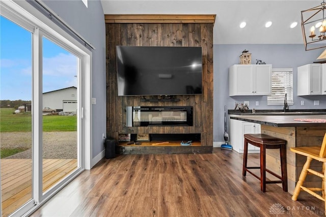 interior space with dark wood-type flooring, a glass covered fireplace, a chandelier, and baseboards