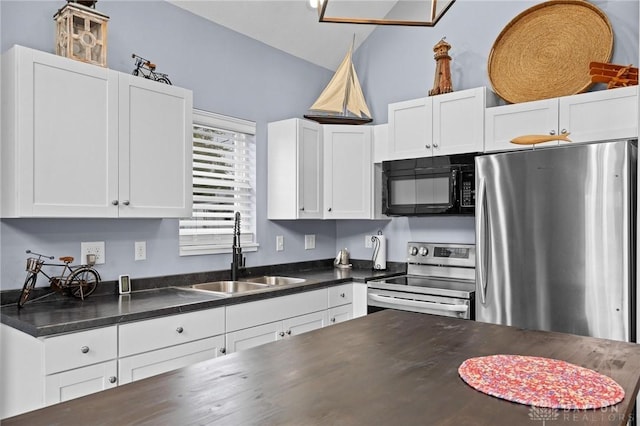 kitchen with stainless steel appliances, dark countertops, a sink, and white cabinets