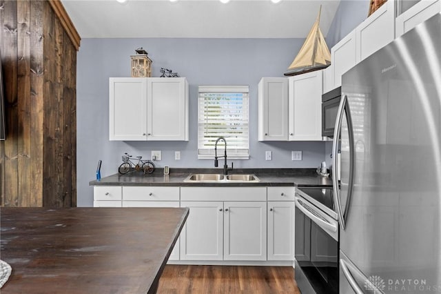 kitchen with stainless steel appliances, butcher block countertops, a sink, and white cabinetry