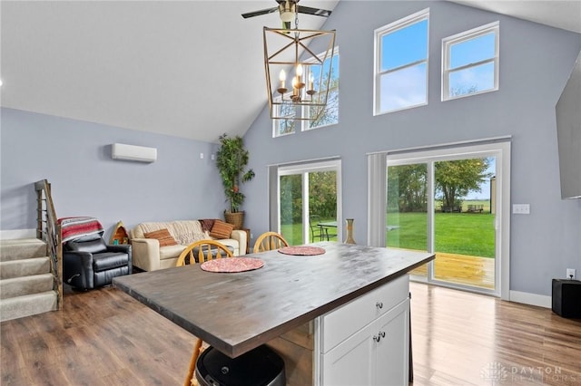 kitchen featuring a breakfast bar area, open floor plan, wood finished floors, white cabinetry, and a wall mounted AC