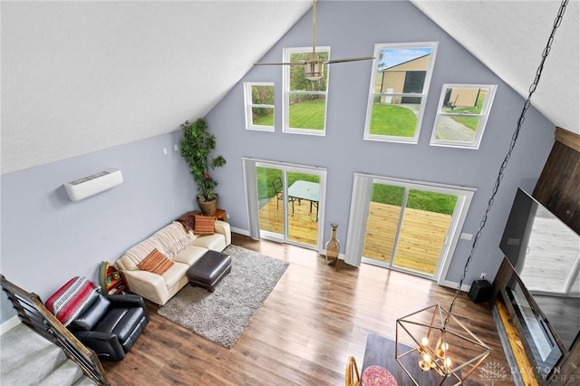 living room featuring hardwood / wood-style floors, a healthy amount of sunlight, vaulted ceiling, and a notable chandelier