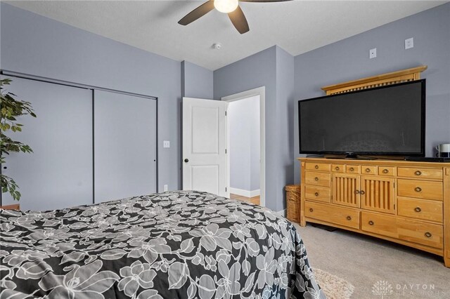 bedroom featuring light carpet, a closet, and ceiling fan