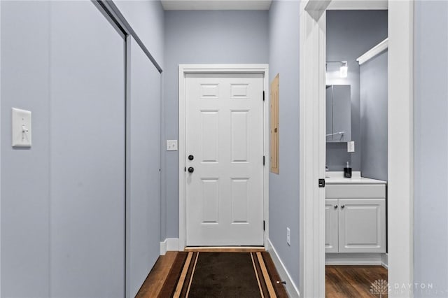 doorway with baseboards and dark wood finished floors