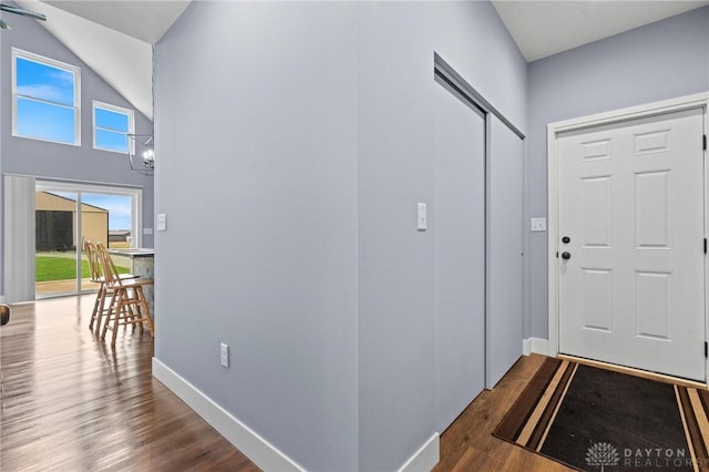 entryway with an inviting chandelier, baseboards, and dark wood-type flooring