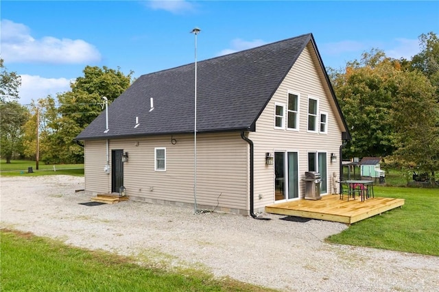 back of property with entry steps, roof with shingles, a lawn, and a wooden deck