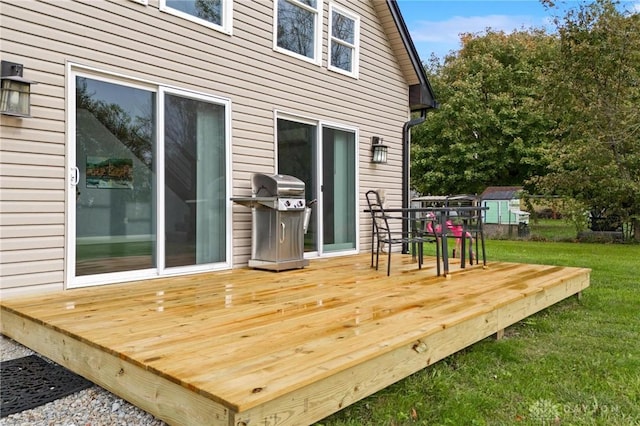 wooden terrace with an outbuilding, a yard, area for grilling, and a storage unit