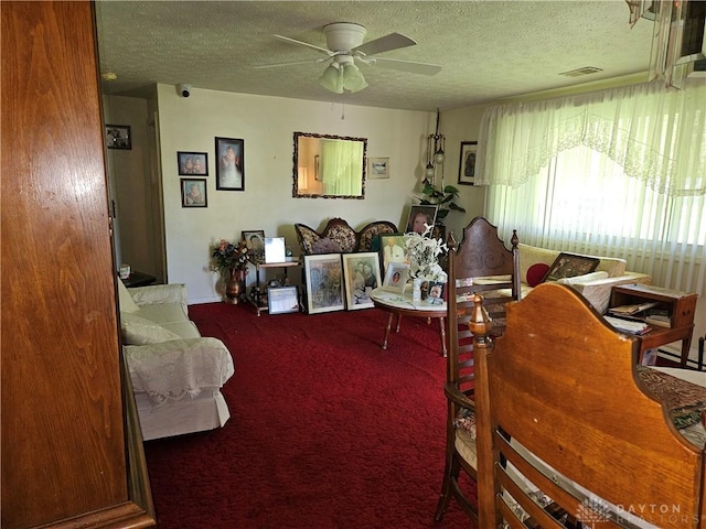 carpeted living room with ceiling fan and a textured ceiling