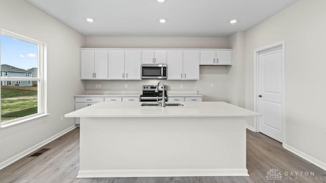 kitchen featuring a center island with sink, sink, white cabinetry, and stainless steel appliances