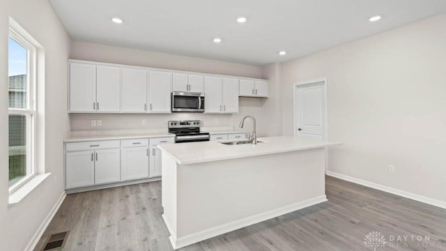 kitchen with appliances with stainless steel finishes, a center island with sink, white cabinetry, and sink