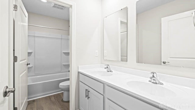 full bathroom featuring hardwood / wood-style floors, vanity,  shower combination, and toilet