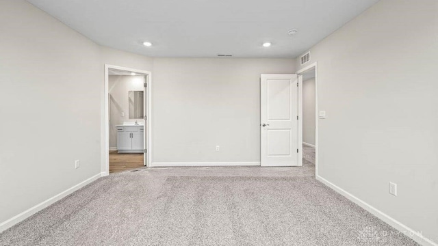 unfurnished bedroom with light colored carpet and ensuite bath