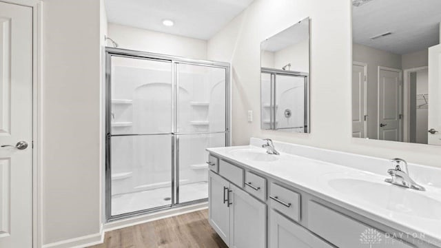 bathroom with hardwood / wood-style floors, vanity, and a shower with shower door