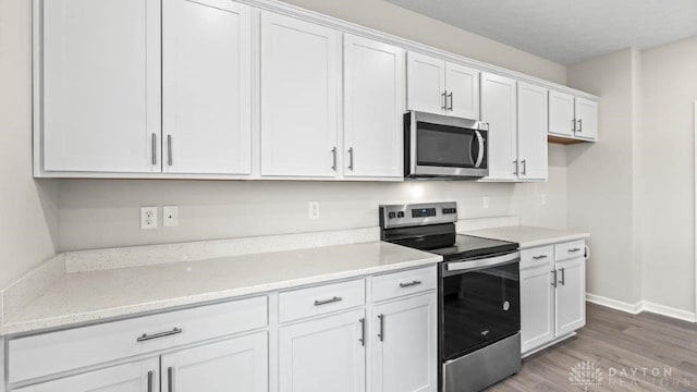 kitchen featuring light stone counters, white cabinets, light hardwood / wood-style floors, and appliances with stainless steel finishes