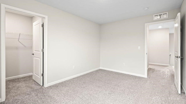 unfurnished bedroom featuring light colored carpet, a spacious closet, and a closet