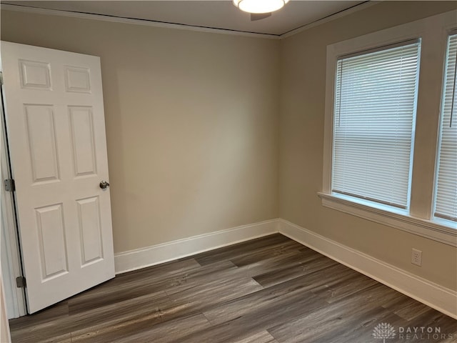 unfurnished room featuring dark wood-type flooring and ornamental molding