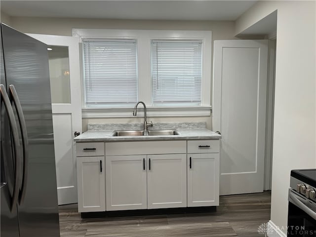 kitchen with dark wood-type flooring, white cabinetry, stainless steel appliances, and sink