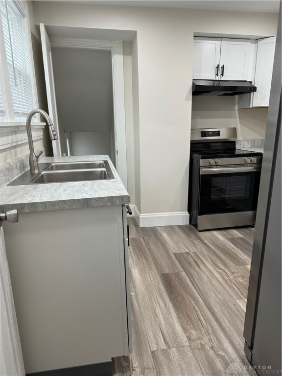 kitchen with white cabinets, stainless steel appliances, sink, and light wood-type flooring