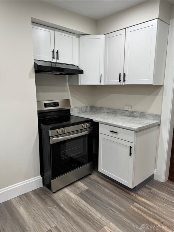 kitchen with electric stove, hardwood / wood-style flooring, and white cabinets