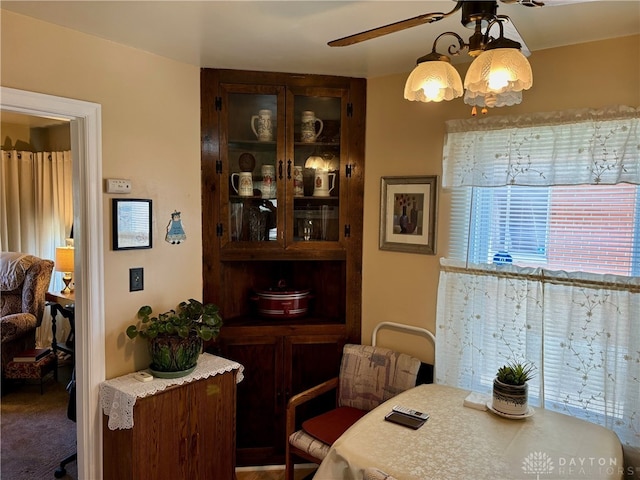 carpeted dining area with ceiling fan