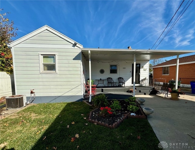 rear view of house with a porch, central AC, and a lawn