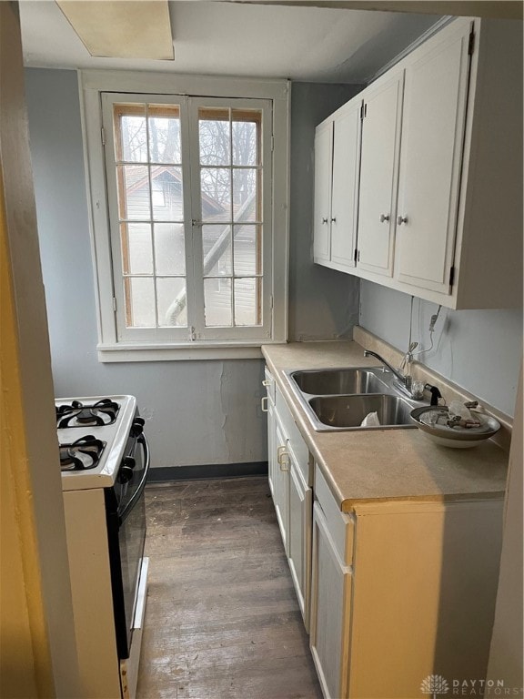 kitchen featuring white range with gas cooktop, white cabinets, sink, and dark wood-type flooring