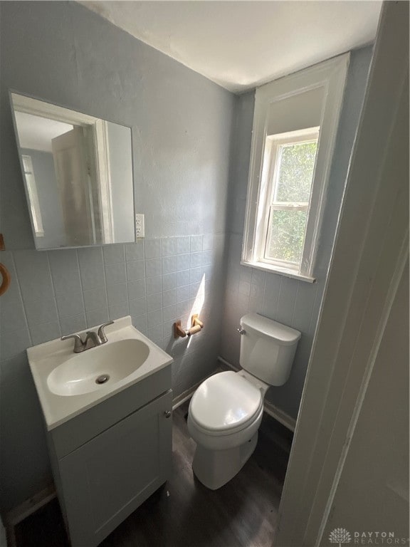 bathroom featuring vanity, toilet, tile walls, and hardwood / wood-style floors