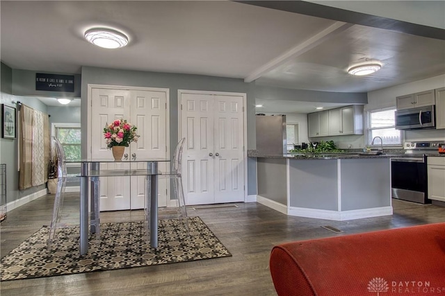 kitchen with dark hardwood / wood-style flooring, gray cabinetry, stainless steel appliances, sink, and dark stone countertops