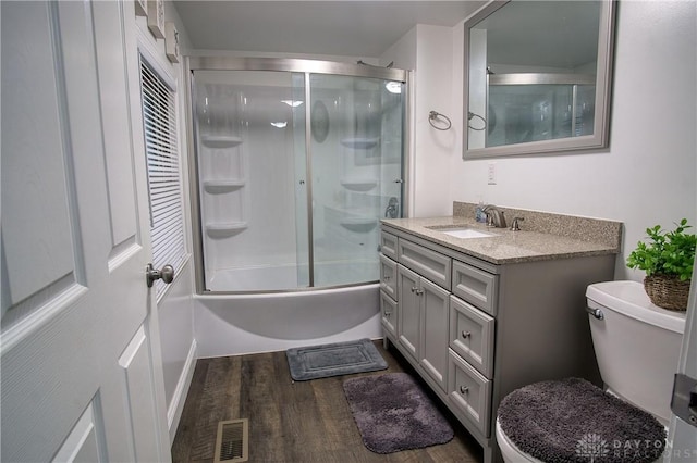 full bathroom with enclosed tub / shower combo, vanity, wood-type flooring, and toilet