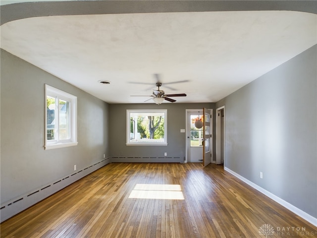 spare room with ceiling fan, wood-type flooring, and a baseboard heating unit