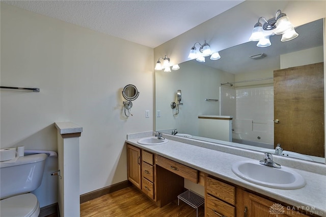 full bathroom featuring vanity, wood-type flooring, a textured ceiling, toilet, and shower / bathing tub combination