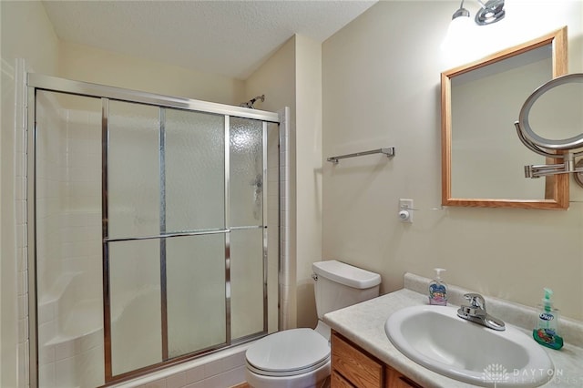 bathroom with toilet, vanity, a textured ceiling, and walk in shower