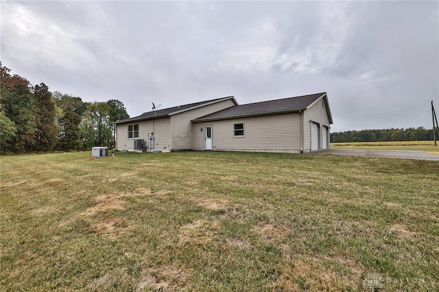 rear view of house featuring a lawn, cooling unit, and a garage