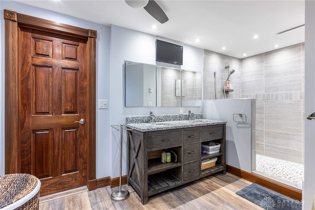 bathroom with vanity, hardwood / wood-style floors, tiled shower, and ceiling fan