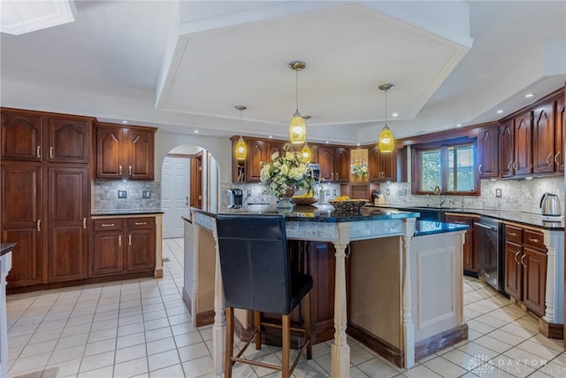 kitchen with a center island, light tile patterned floors, stainless steel dishwasher, a tray ceiling, and pendant lighting