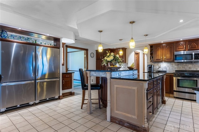 kitchen featuring a kitchen bar, hanging light fixtures, appliances with stainless steel finishes, a kitchen island, and backsplash