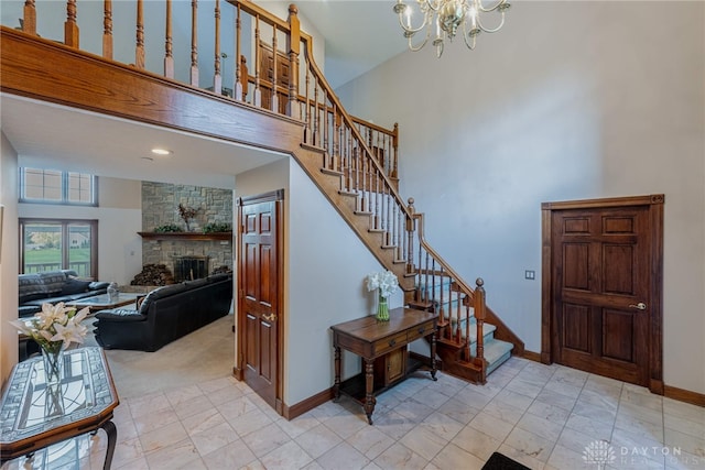 interior space with a high ceiling, a stone fireplace, and a notable chandelier